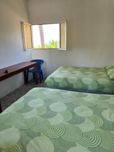 Un dormitorio con dos camas y un escritorio y una ventana. en Cabañas Edda, en Puerto Escondido