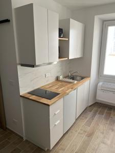 a kitchen with white cabinets and a sink at Renovated Seaside Studio in the Heart of Menton in Menton