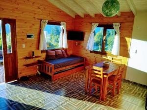 a room with a bed and a table in a cabin at Cabaña Los Chochos in Lago Puelo