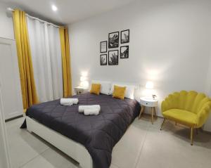 a bedroom with a large bed and a yellow chair at Le Popolari - Appartamento in Bitonto