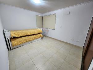 ein kleines Zimmer mit einem Bett und Fliesenboden in der Unterkunft Lago los Molinos Punto Claro villa Silvestre depto 2 dorm y cochera in Villa Ciudad Parque