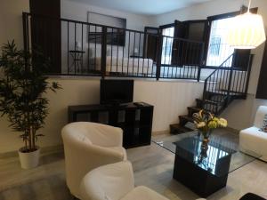 a living room with a white chair and a table at Málaga Apartamentos - Jinetes, 13 in Málaga