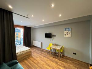 1 dormitorio con 1 cama, mesa y sillas amarillas en Cozy apartment in NEW GUDAURI Block F2, en Gudauri