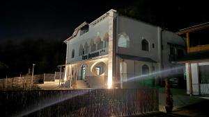 a white building with lights on it at night at Casa Basarab in Călimăneşti