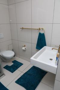 a bathroom with a sink and a toilet and blue rugs at Stylish and Modern Oasis in Windhoek