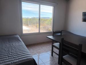 a bedroom with a bed and a table and a window at Cabañas Jugueze San Rafael in San Rafael