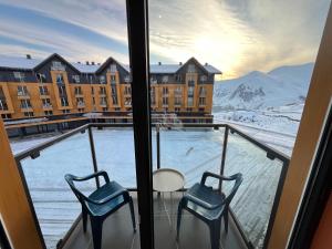 balcón con 2 sillas y vistas a un edificio en Cozy apartment in NEW GUDAURI Block F2, en Gudauri