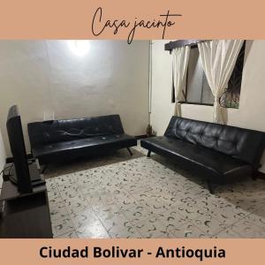 a living room with a black leather couch and a tv at Casa Jacinto in Ciudad Bolívar +2 photos