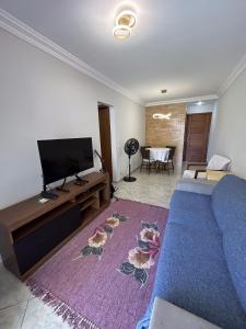 Apartamento na Quadra da Praia! في فيلا فيلها: غرفة معيشة مع أريكة زرقاء وتلفزيون