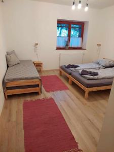 a room with two beds and a red rug at Rozália Vendégház in Pázmánd