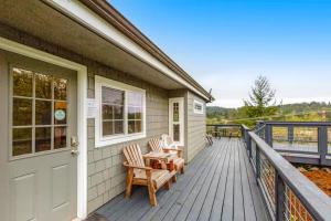 - une terrasse couverte avec 2 chaises et une porte dans l'établissement Deer Harbor Cottage & Suites, à Eastsound