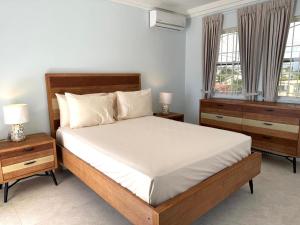 a bedroom with a bed with two night stands and two windows at Silver Sands Beach Villas are great for family-friendly activities in Christ Church