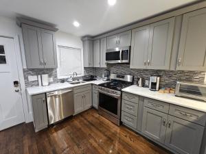 a kitchen with stainless steel appliances and wooden floors at Brand New 4BR House 20Min Downtown Boston in Boston