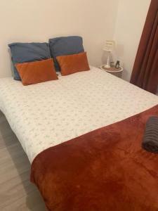 a bed with orange and blue pillows on it at Séjour proche Paris & Disney in Lésigny