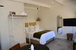 a bedroom with a bed and a table and a tv at House on Pringle in Cape Town