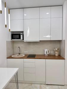 een witte keuken met witte kasten en een spoelbak bij Elen's Bi Residence in Batoemi