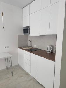 een keuken met witte kasten, een wastafel en een tafel bij Elen's Bi Residence in Batoemi