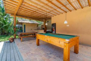 a patio with a pool table and a wooden pergola at Casa Theo Trancoso in Trancoso