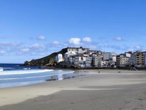 a view of a beach with buildings and the ocean at Camiño dos faros Malpica in Malpica