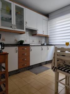 a kitchen with white cabinets and a table at Camiño dos faros Malpica in Malpica