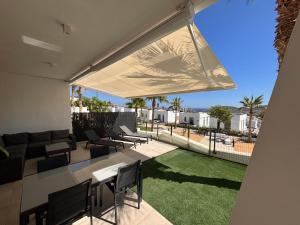 eine Außenterrasse mit einem Tisch, Stühlen und Gras in der Unterkunft Martormar in Finestrat