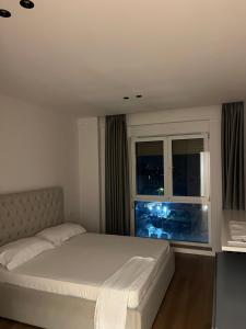 ティラナにあるRenas apartmentの白いベッドと窓のある寝室