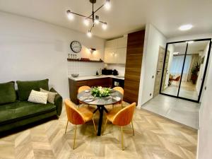 a living room with a table and a green couch at Alėjos Apartmentai City in Druskininkai