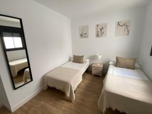 a white room with two beds and a mirror at Luxury penthouse with pool near Fuengirola beach in Fuengirola
