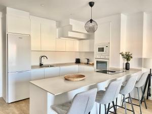 a kitchen with white cabinets and a island with stools at Luxury penthouse with pool near Fuengirola beach in Fuengirola