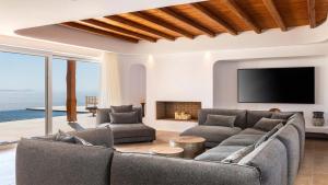 a living room with a couch and a tv at Ria Mar Villas & Suites by Live&Travel in Houlakia