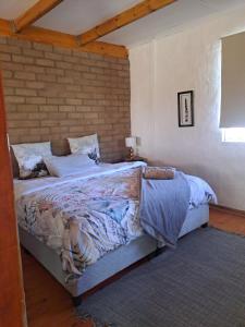 ein Bett in einem Schlafzimmer mit Ziegelwand in der Unterkunft Mount Gerizim Farm in Louisvale