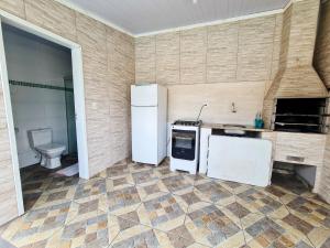 a kitchen with a refrigerator and a stove and a sink at Casa das Flores com piscina in Matinhos