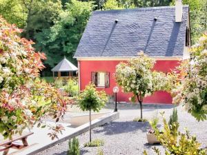 ein rotes Haus mit Bäumen im Garten in der Unterkunft Moulin Vrindavan, Havre de paix en pleine nature à Eysus in Eysus