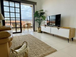 ein Wohnzimmer mit Fernseher und Sofa in der Unterkunft Apartamento con piscina junto al mar in Arona