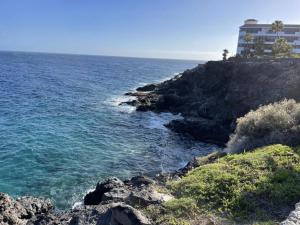 ein Gebäude auf einer Klippe am Meer in der Unterkunft Apartamento con piscina junto al mar in Arona