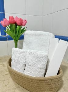 ein Korb mit Handtüchern und einer Vase rosa Blumen in der Unterkunft Apartamento con piscina junto al mar in Arona