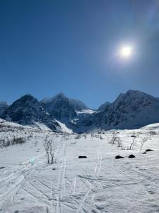 a snow covered mountain with the sun in the sky at Flott enebolig nær naturen in Lyngen