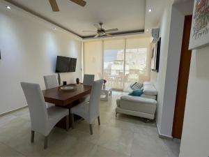 a dining room with a table and chairs and a couch at Central Luxury Apartment Playa del Carmen in Playa del Carmen