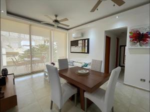 a dining room with a wooden table and white chairs at Central Luxury Apartment Playa del Carmen in Playa del Carmen