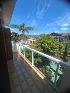 a balcony with a view of the ocean and palm trees at Casa Tapajos in Ubatuba