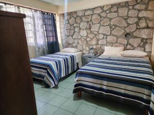 two beds in a room with a stone wall at Casa Gomez in Taxco de Alarcón