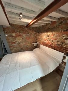 a white bed in a room with a brick wall at La stanza dei citti-Lapo in Arezzo