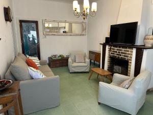 a living room with white furniture and a fireplace at Casa Tradicional del Barrio de la Estación in Tandil