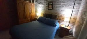 a bedroom with a blue bed and a brick wall at los pepes in Las Grutas