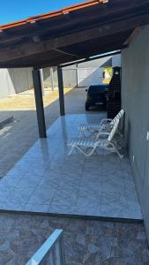 2 sedie bianche sedute su un patio con auto di Casa em Pirambu a Pirambu 1 altra foto