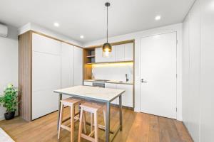 a kitchen with a table and two stools at Perfectly Located Executive 1BR at Caulfield North in Melbourne