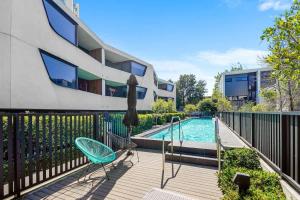a deck with chairs and an umbrella and a swimming pool at Perfectly Located Executive 1BR at Caulfield North in Melbourne