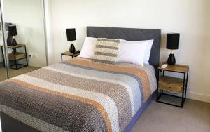 ジーロングにあるMERCER APARTMENTS 2 Bedroom Apartment with Bay Views on the Geelong Waterfront - 711の大きなベッドと2つのナイトスタンドを備えた寝室