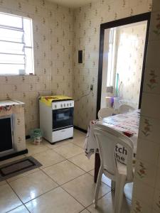 a kitchen with a stove and a table with chairs at Apartamento Iguaba Grande, bairro Canellas City , Condomínio Claudia, em frente ao Quiosque do popeye in Iguaba Grande
