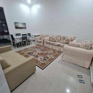 een woonkamer met banken en een tapijt bij OLIA MEDINA KERTEH 4 BILIK HOMESTaY in Kampong Kemaman